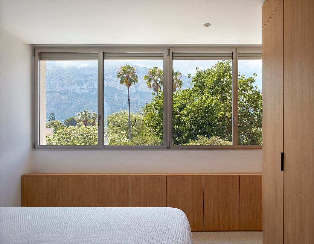 Large windows framing lush, mountainous greenery create a serene, nature-inspired space.