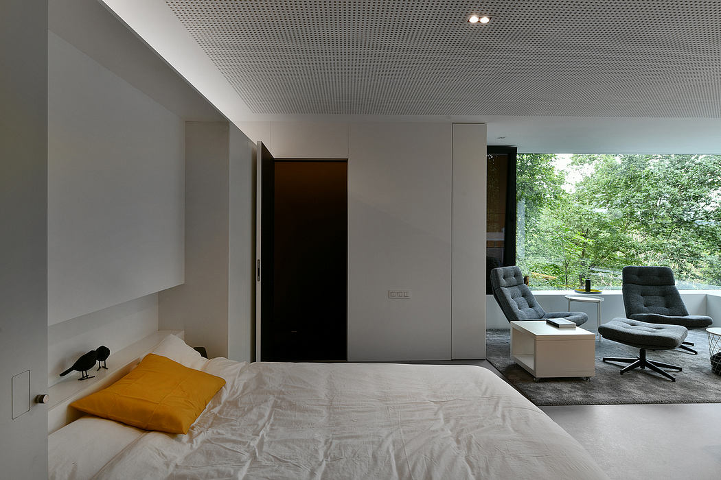 Minimalist bedroom with floor-to-ceiling windows, built-in furniture, and a cozy seating area.