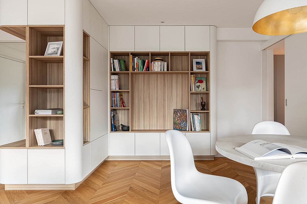 Modern, minimalist interior with built-in wood-paneled shelving, white chairs, and herringbone floors.