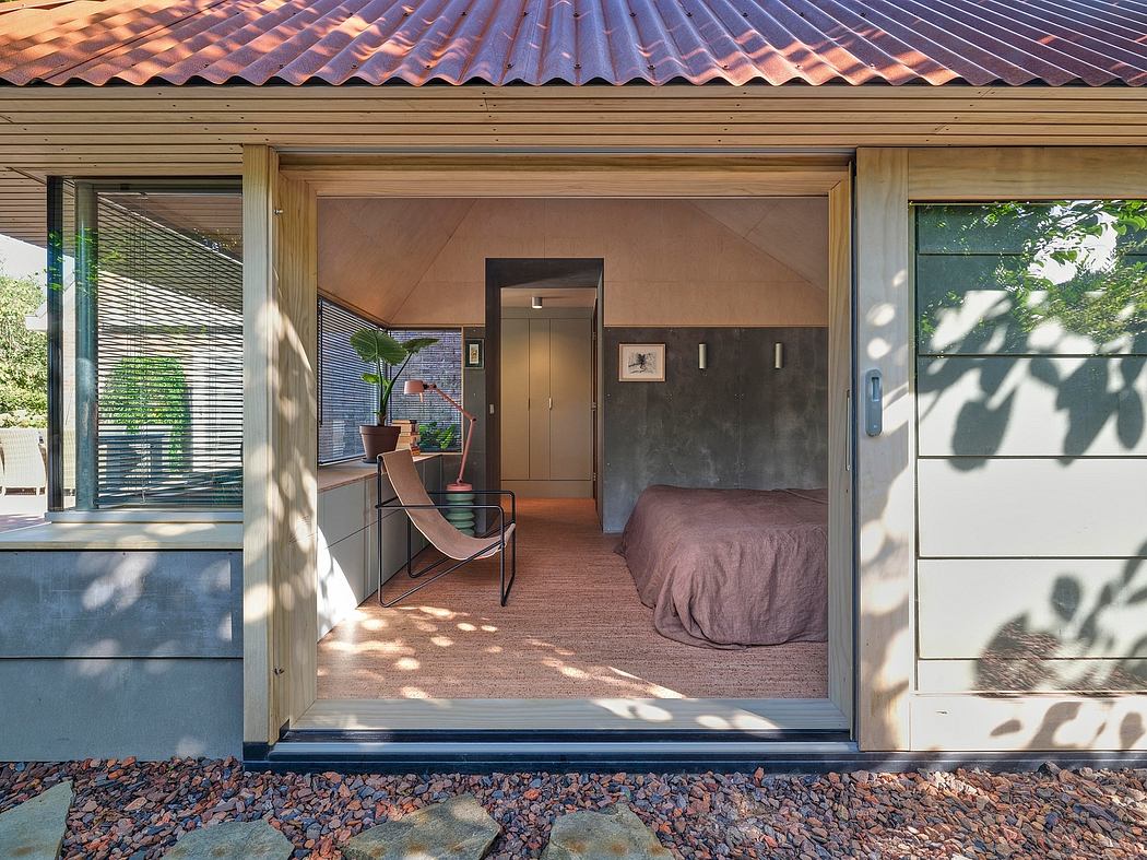 A rustic bedroom inside a modern, glass-walled home with a tiled roof and stone floor.
