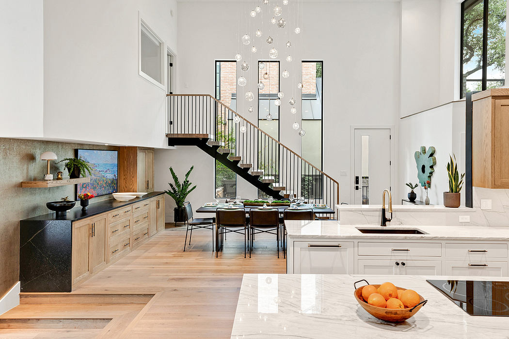 Sleek modern kitchen with wooden cabinetry, marble counters, and a striking staircase.