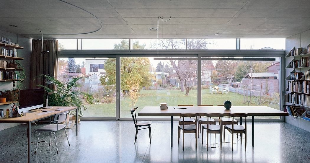 Airy, minimalist living space with large windows, concrete floors, and dining table.