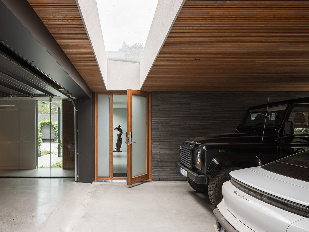 Spacious garage interior with modern wooden ceiling, sleek black vehicles, and glass entryway.