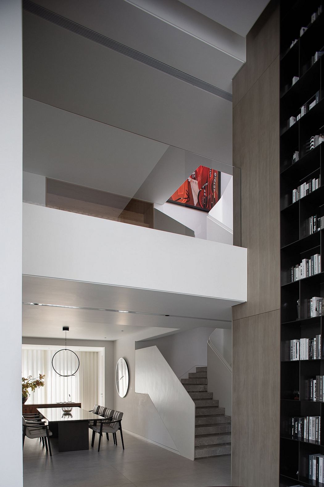 Modern open-plan layout with geometric stairs, built-in bookshelf, and bold red artwork.