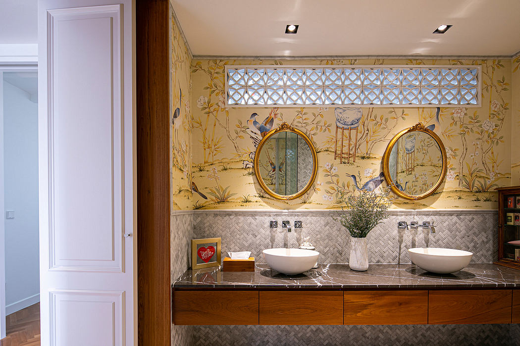 Ornate bathroom with gold-framed mirrors, patterned wallpaper, and a marble vanity.