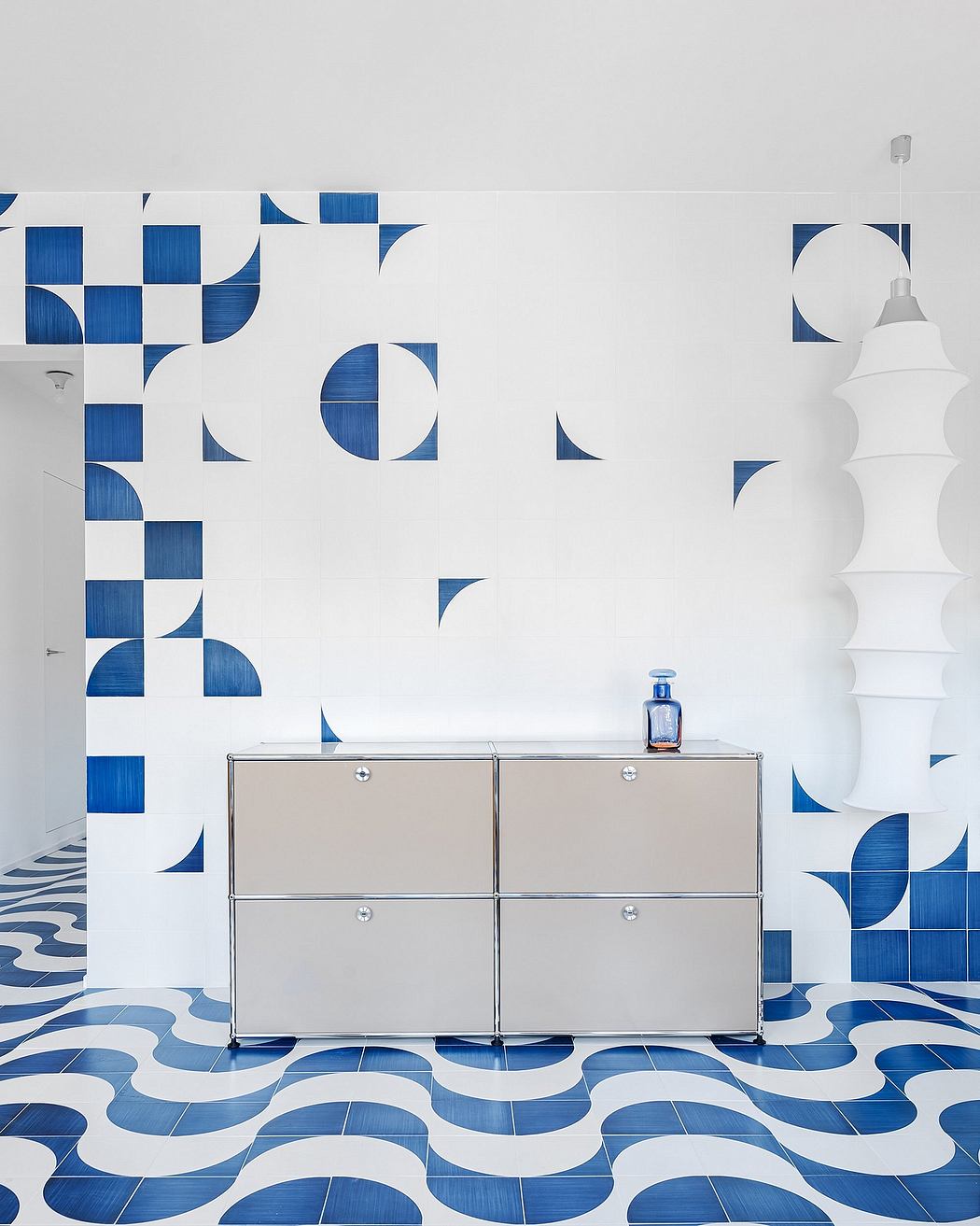 Sleek storage unit with geometric blue-and-white wall mural and pendant lamp.