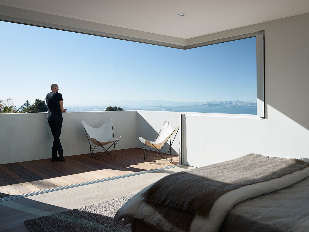 A modern bedroom with floor-to-ceiling windows, wooden flooring, and minimalist furniture, offering a stunning city view.