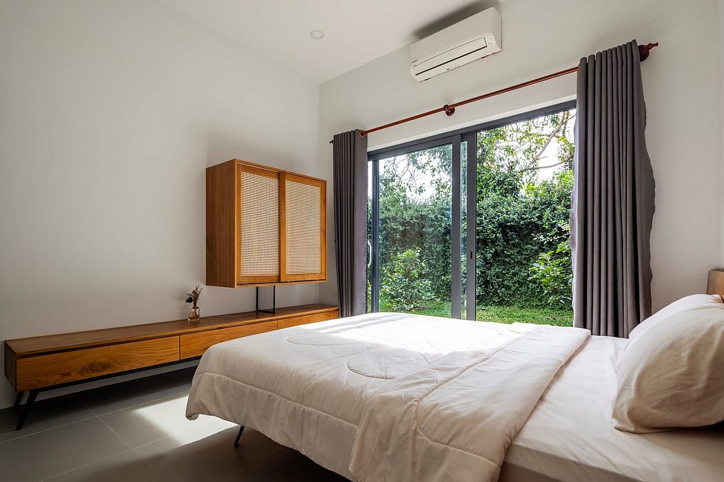 Cozy bedroom with modern wooden furniture, large window overlooking lush greenery.