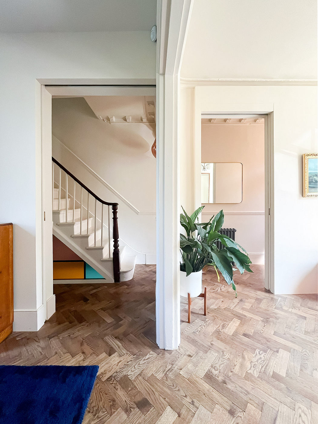 Cozy interior with parquet flooring, stairway, and lush plant in corner.