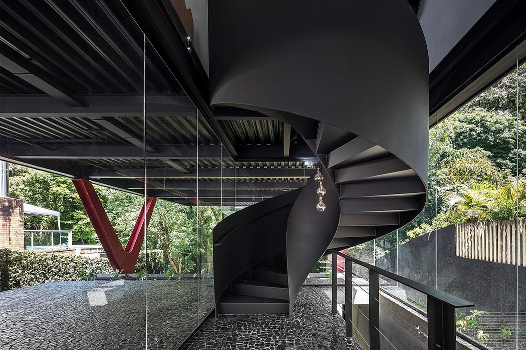 A modern, spiral staircase with a striking black and red color scheme in a glass-walled pavilion.