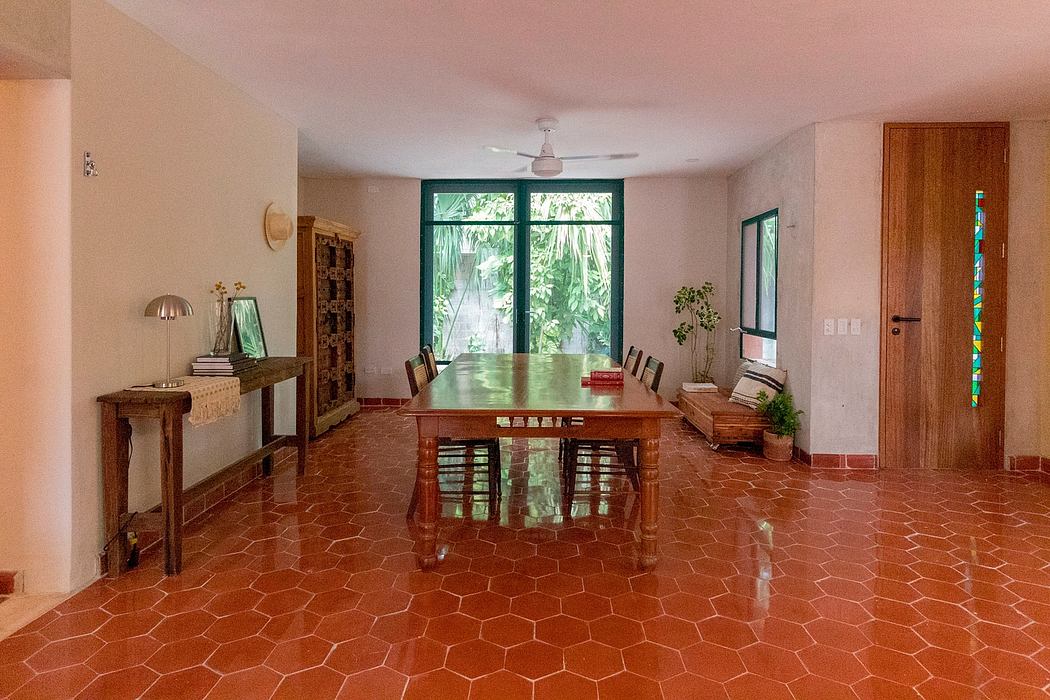 A cozy interior featuring a wood dining table, tiled floors, and large windows overlooking greenery.