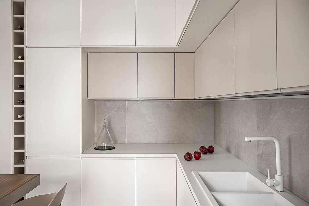 A modern kitchen design with minimalist white cabinetry, sleek gray backsplash, and a built-in storage unit.