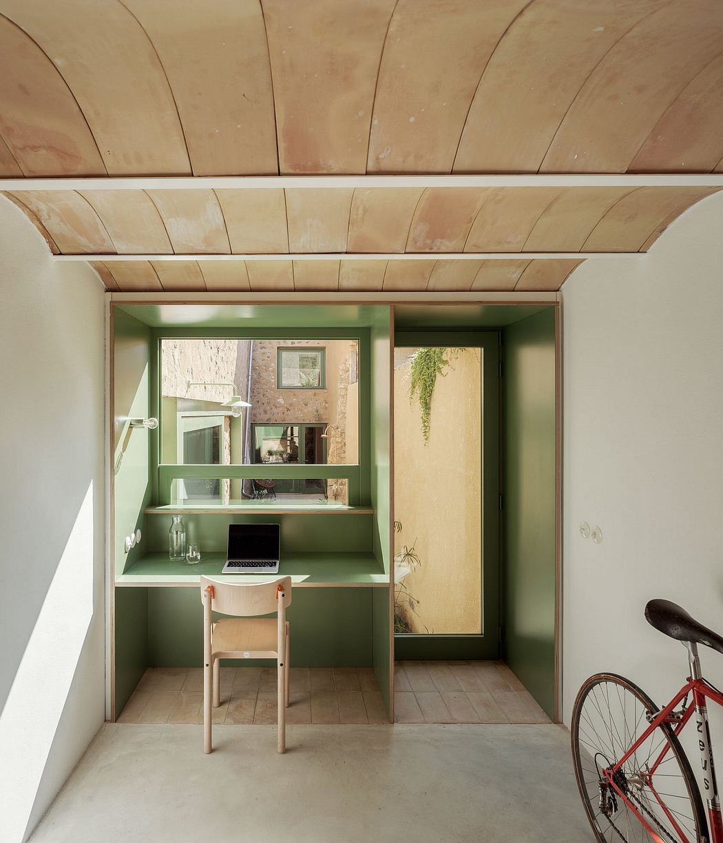 A cozy workspace nook with built-in shelving, wooden ceiling, and a red bicycle.