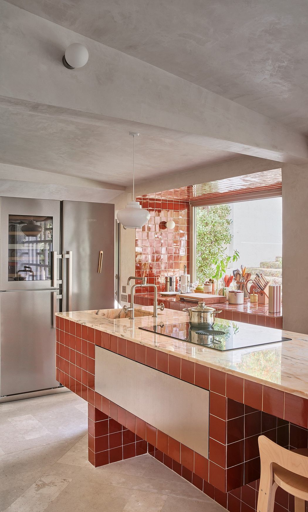 A modern kitchen with striking orange tile cladding, natural lighting, and a sleek countertop.