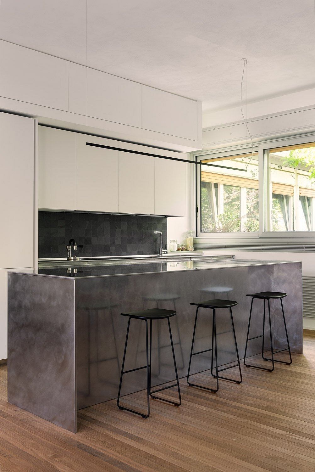 Sleek, minimalist kitchen with concrete countertops, black cabinetry, and modern bar stools.
