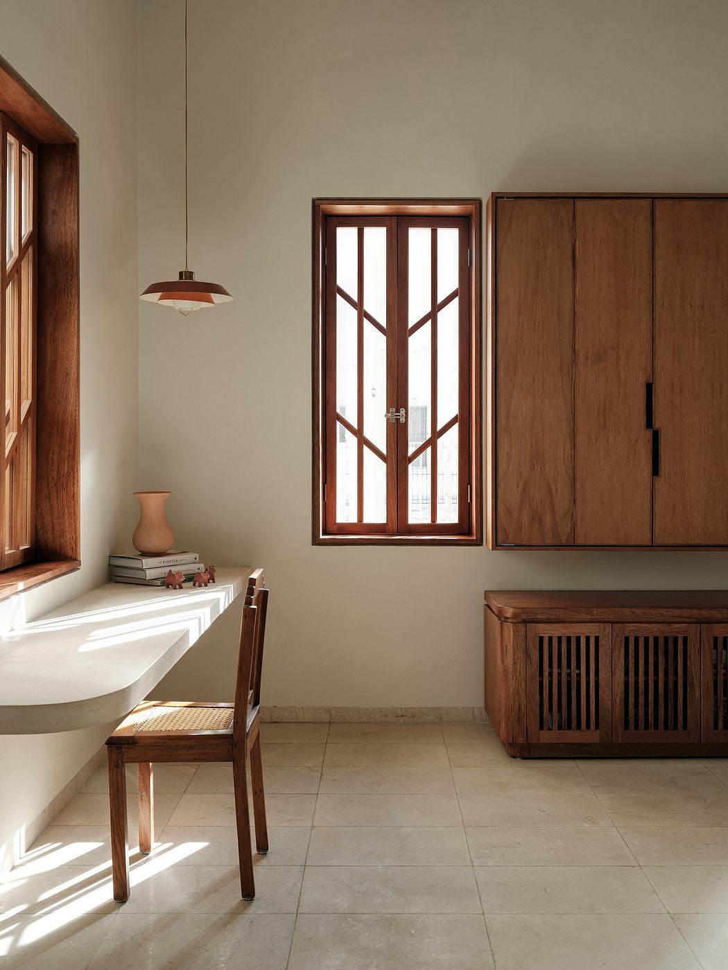 Warm, minimalist interior with wooden furniture, tile flooring, and a large window.