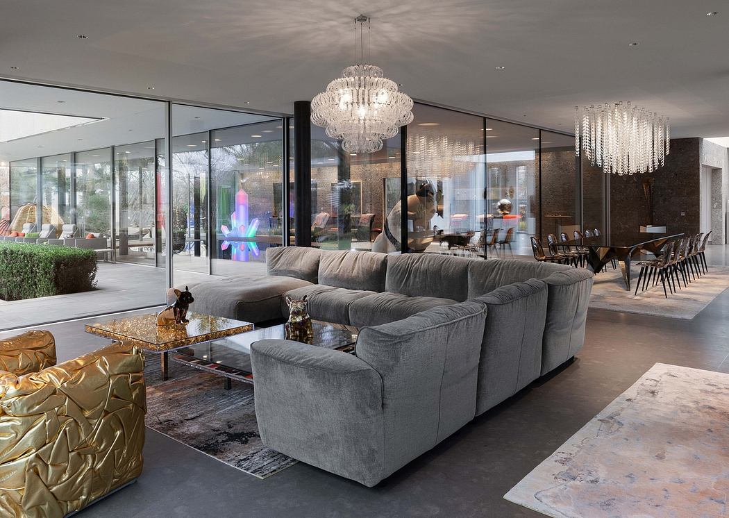 Expansive glass walls, plush gray sofas, and a grand crystal chandelier adorn this lavish interior.