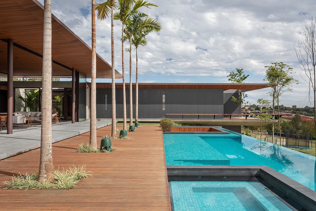 Sleek modern architecture with a large swimming pool, wooden deck, and palm trees.