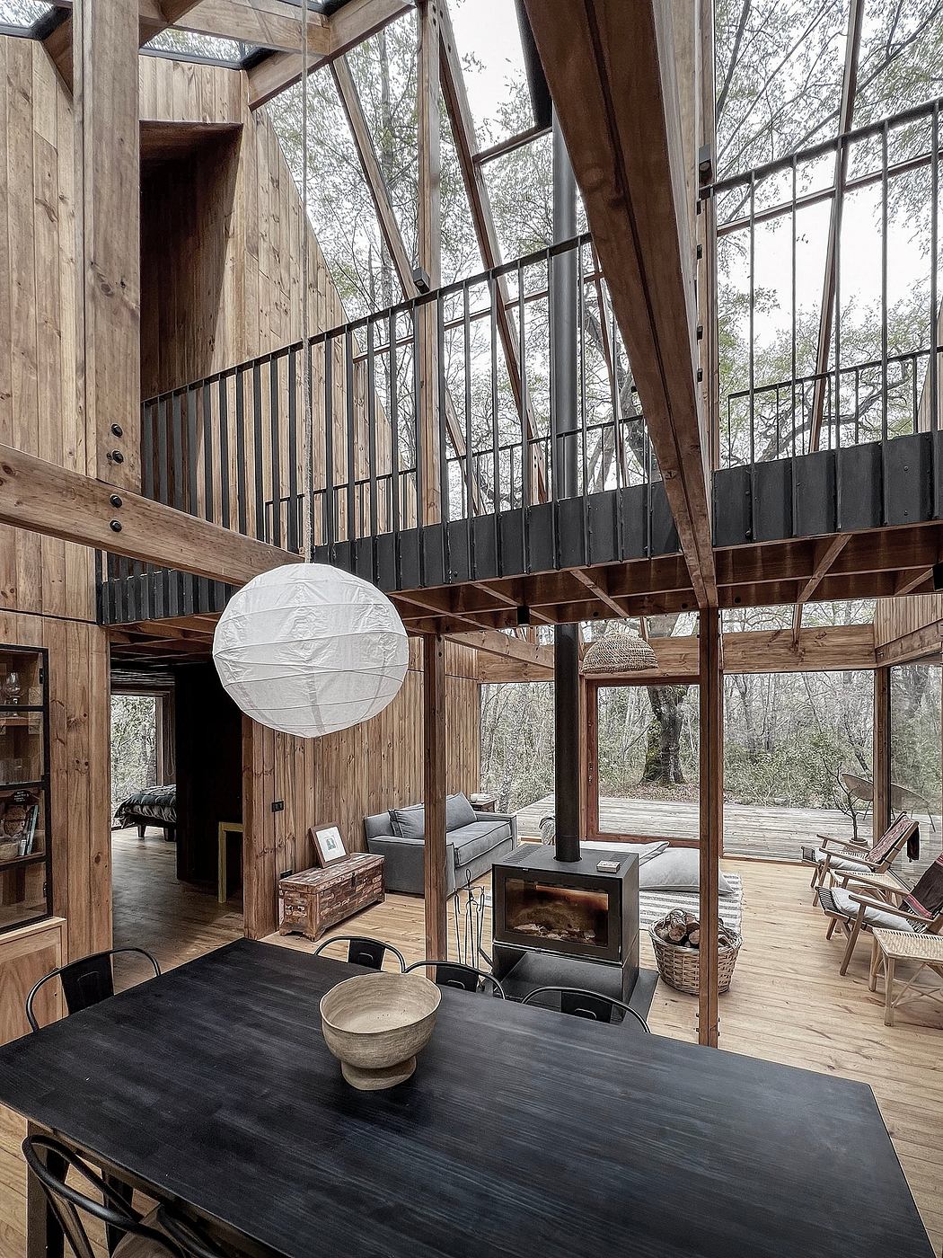 A cozy cabin with wooden beams, high ceilings, and large windows overlooking a lush forest.