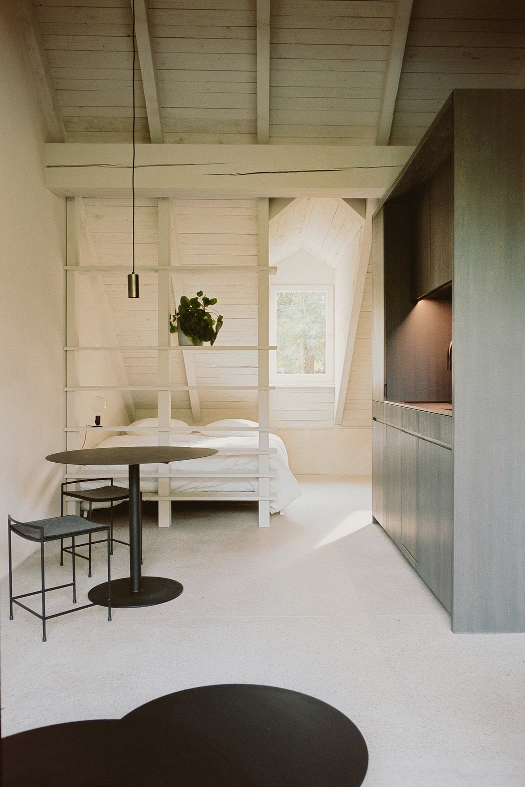 A cozy loft-like space with a minimalist, rustic design featuring wooden beams and furniture.