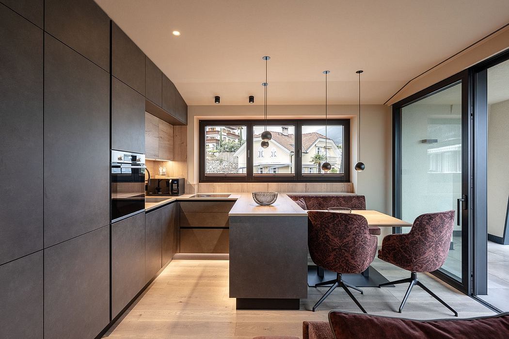 Modern kitchen with dark cabinetry, large windows, and patterned dining chairs.