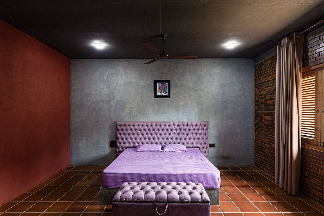 Cozy bedroom with a plush, tufted purple headboard, hardwood floors, and rustic brick walls.