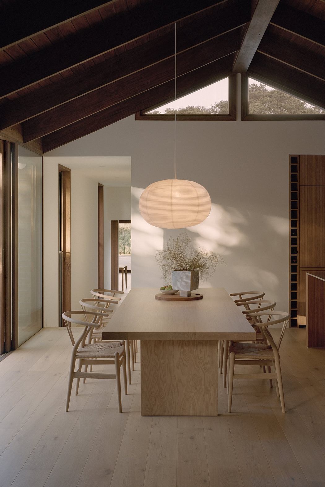 Rustic dining room with vaulted ceiling, wood paneling, and mid-century modern furnishings.