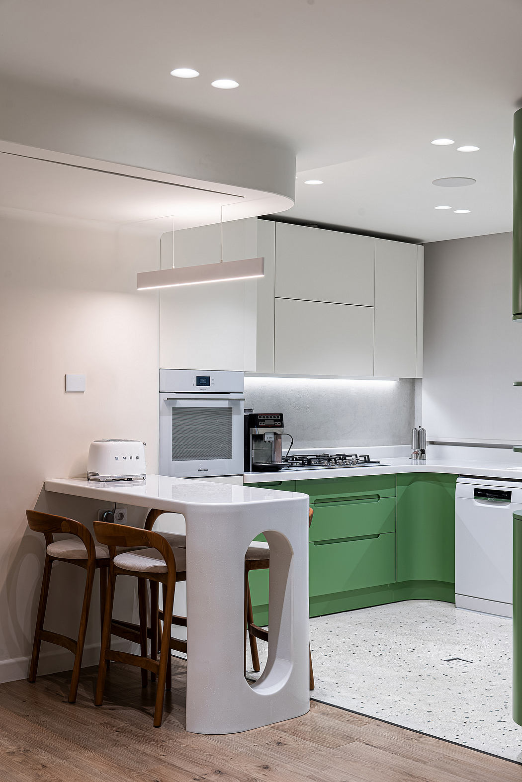 Sleek, modern kitchen with minimalist green cabinets, pendant lighting, and wooden barstools.