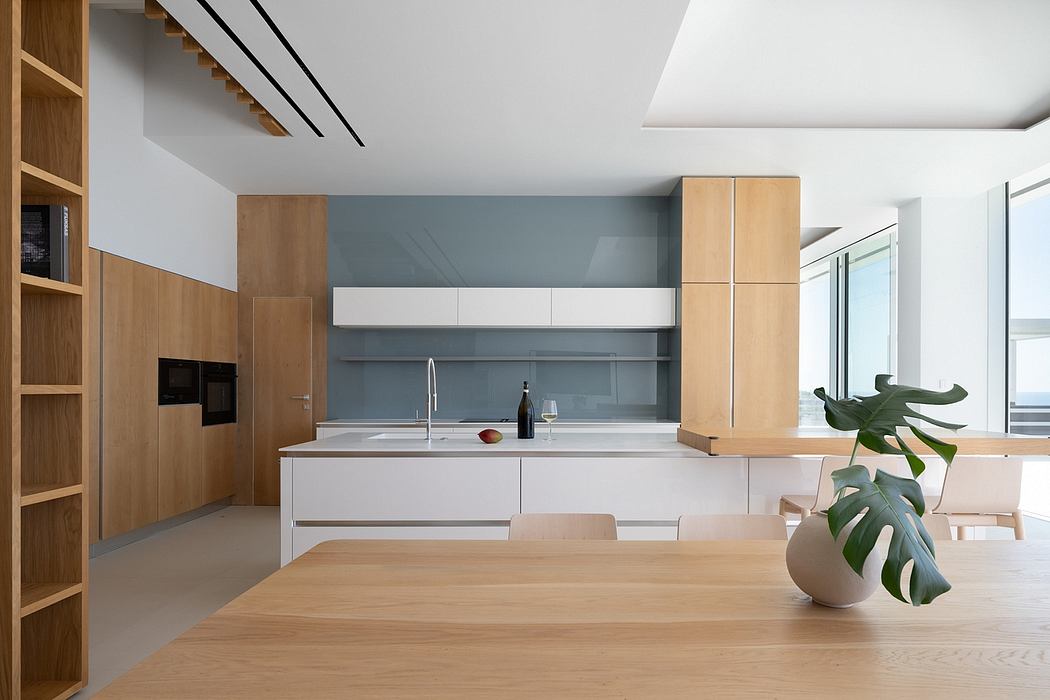A modern kitchen with sleek white cabinets, natural wood accents, and a large dining table.