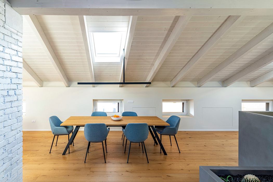 Spacious open-plan loft with natural lighting, exposed wooden beams, and modern furnishings.