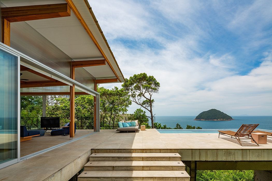 A modern, open-concept home with a pool, ocean view, and a wooden deck.