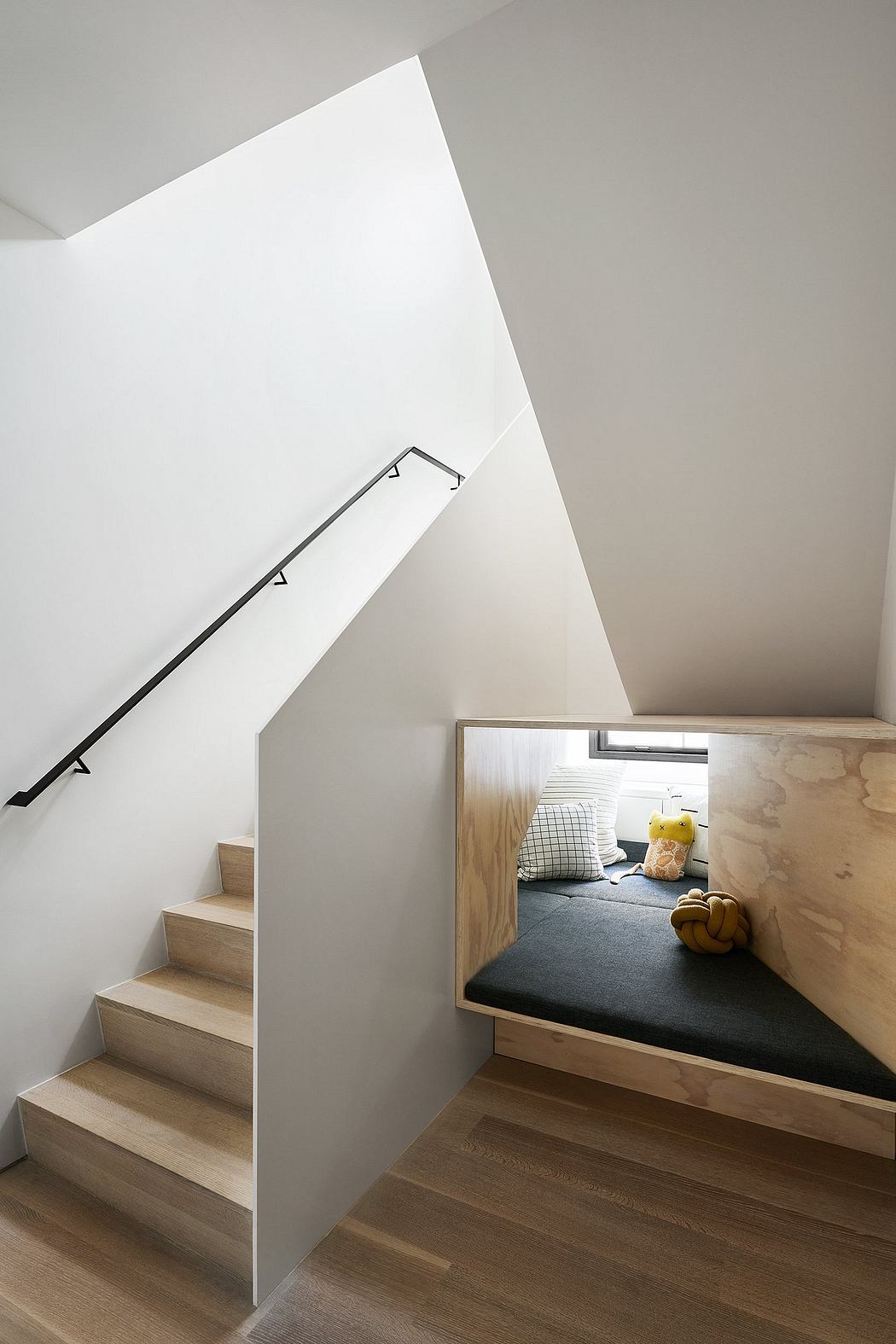 Minimalist staircase with built-in seating nook and modern architectural elements.