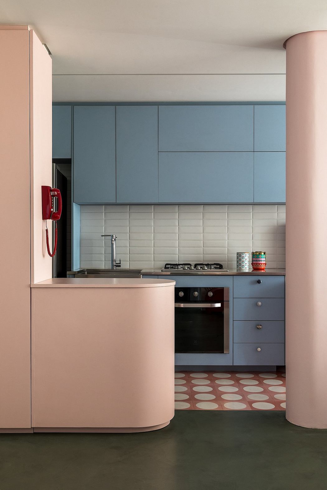 A modern kitchen with sleek gray cabinets, white subway tiles, and a unique patterned floor.