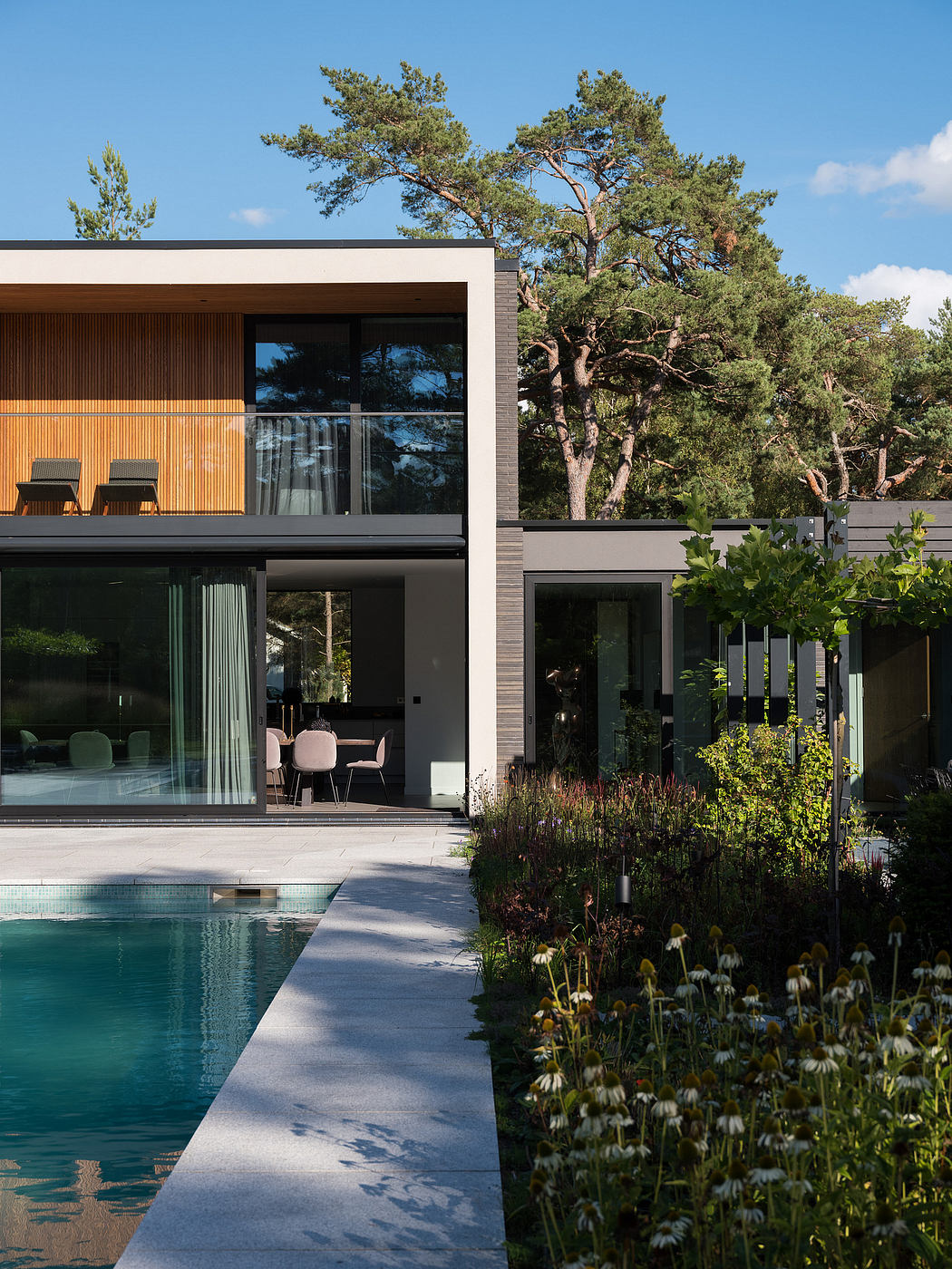 A modern, architecturally-designed house with a swimming pool, surrounded by lush greenery.