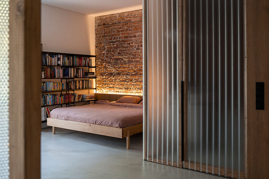 Cozy bedroom with exposed brick wall, minimalist wooden bed frame, and built-in bookshelves.