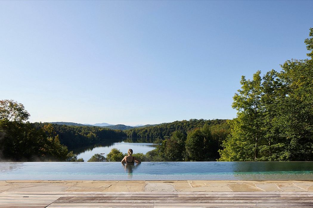 Serene infinity pool overlooking lush forested landscape and lake. Peaceful natural setting.