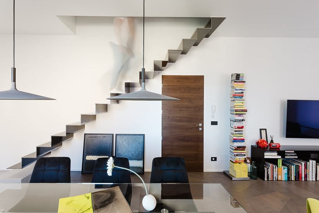 Modern interior with minimalist wooden staircase, pendant lights, and wall art.