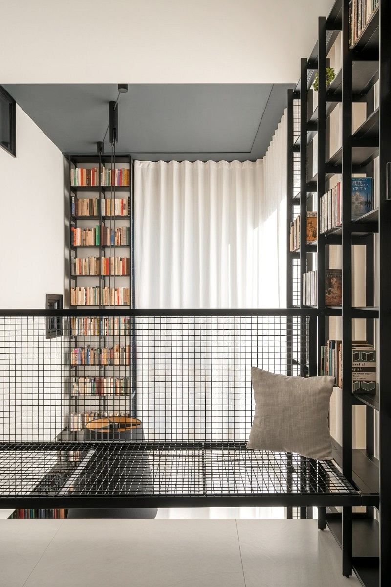 Minimalist living space with sleek black metal shelves, curtains, and a cozy reading nook.