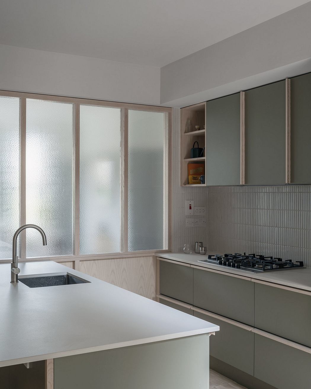 Minimalist kitchen with glazed walls, built-in cabinets, and a sleek white countertop.