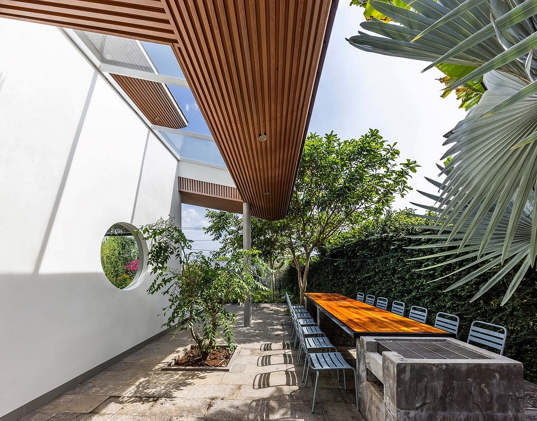 Sleek wooden architecture with lush greenery, outdoor seating, and a circular mirror feature.