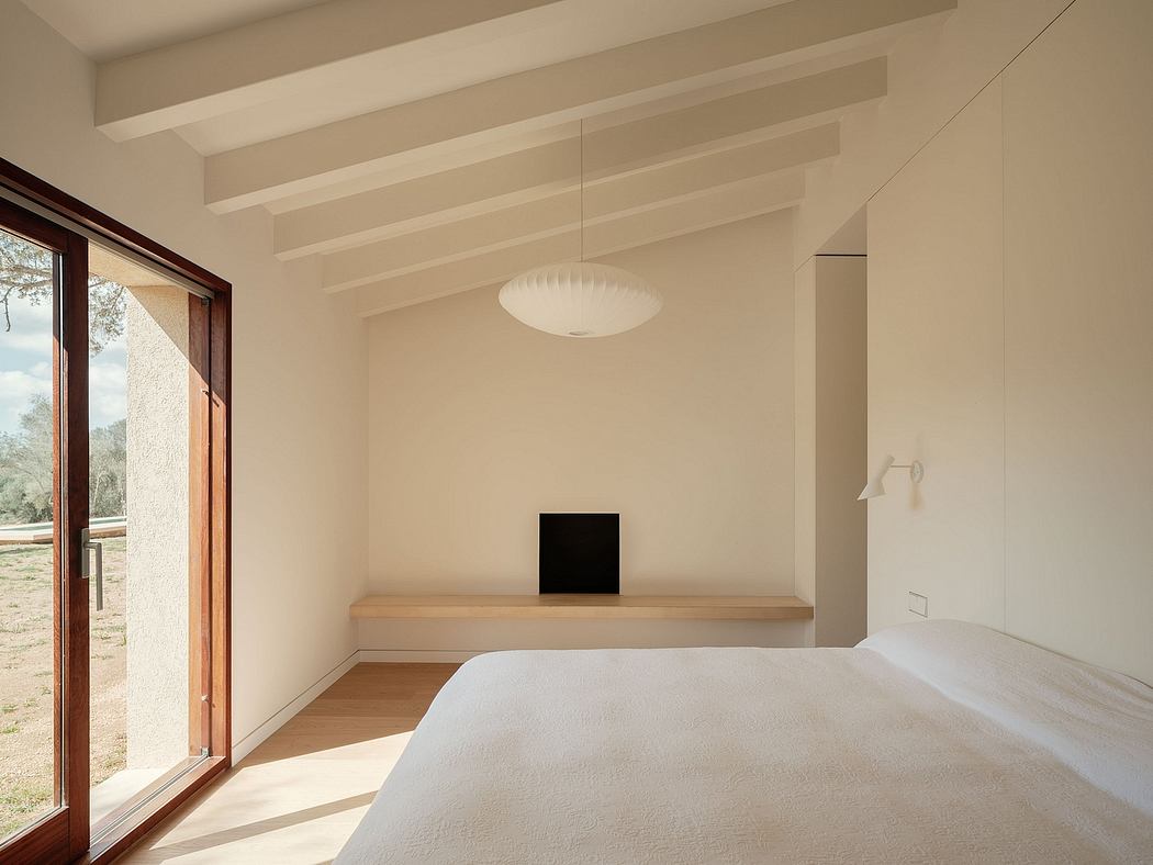 Minimalist bedroom with exposed beams, large window, and wood-topped bench.