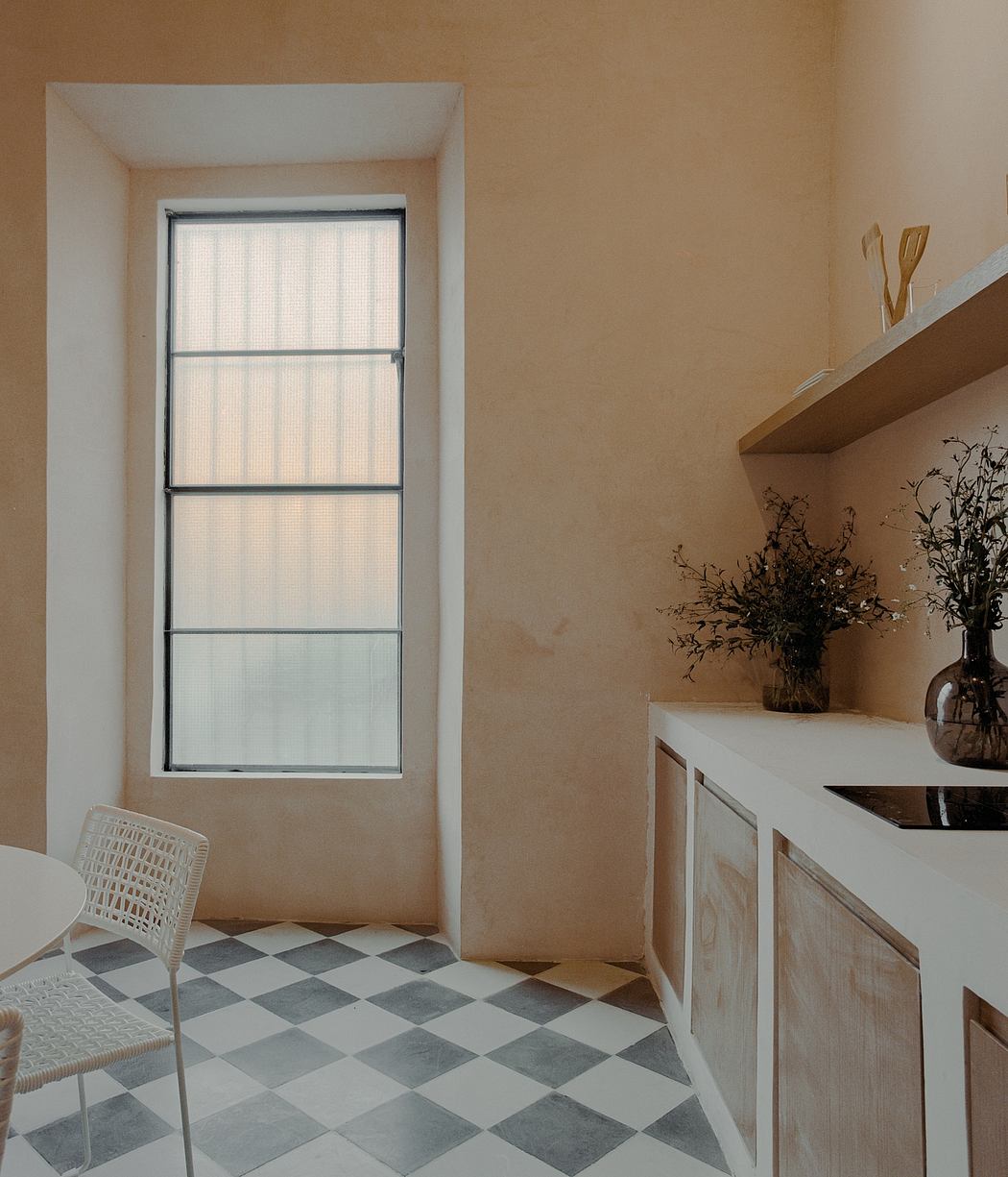 Cozy room with geometric tile flooring, minimalist furniture, and a decorative flower arrangement.