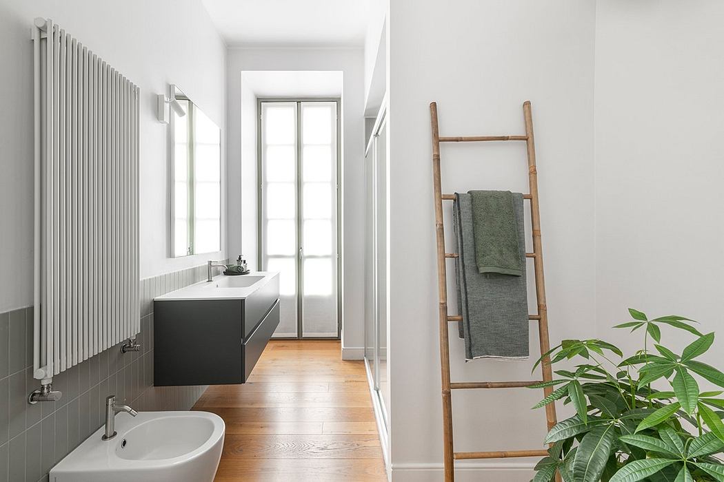 A modern, minimalist bathroom with a sleek vanity, tall radiator, and bamboo towel rack.