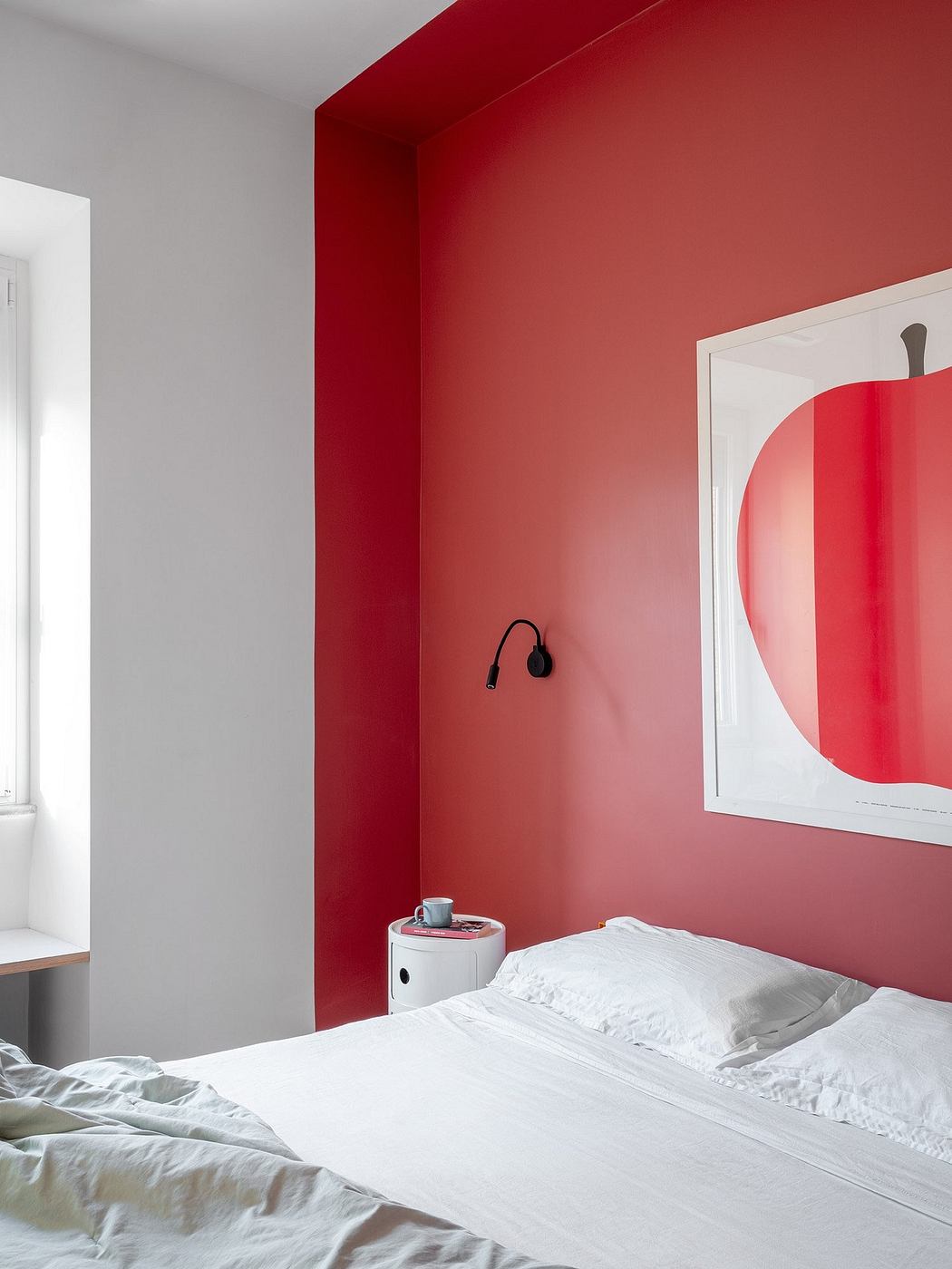 A modern bedroom with a bold red accent wall and a framed circular artwork.