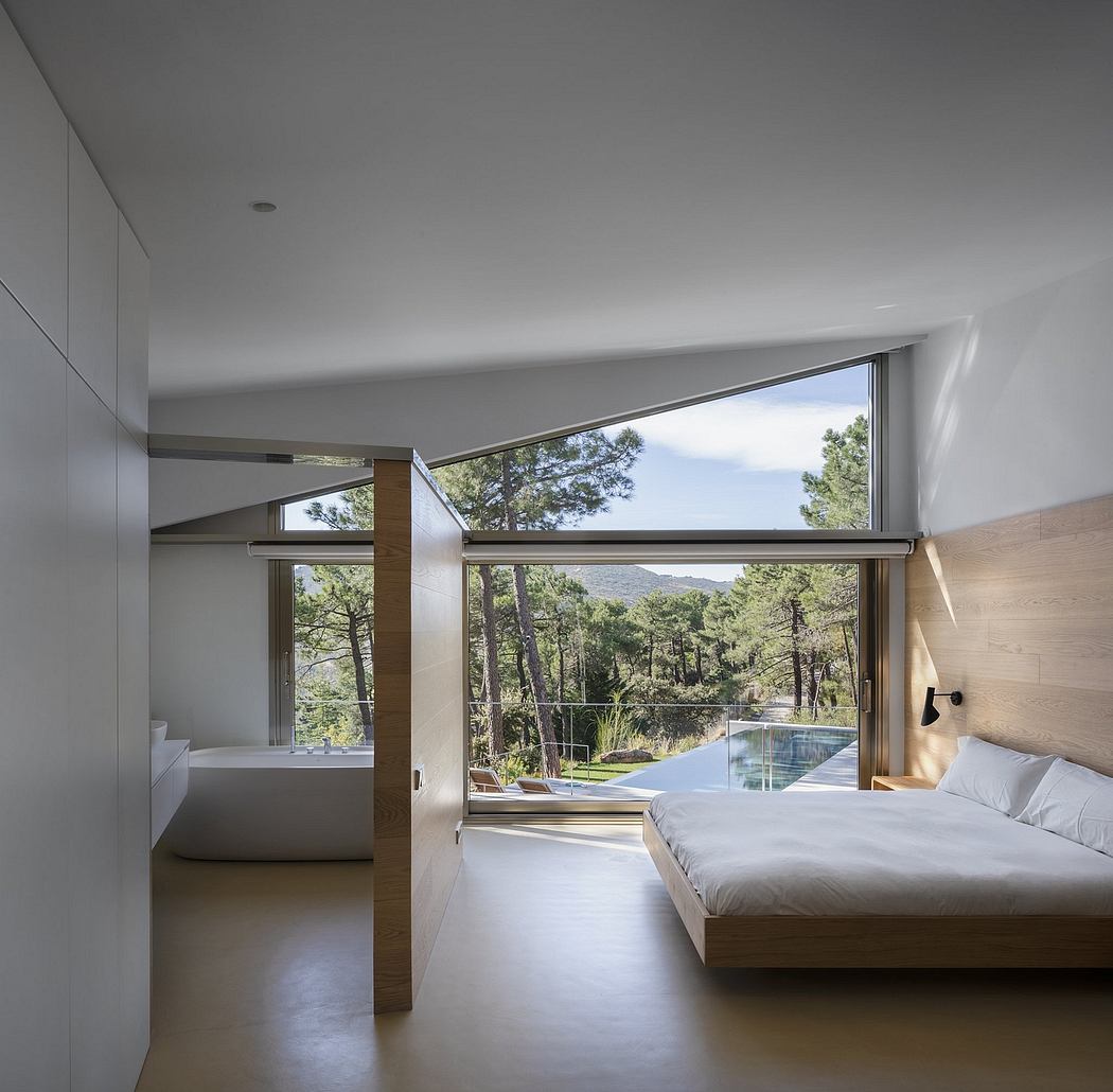 A spacious modern bedroom with large windows offering a scenic forest view and a pool.