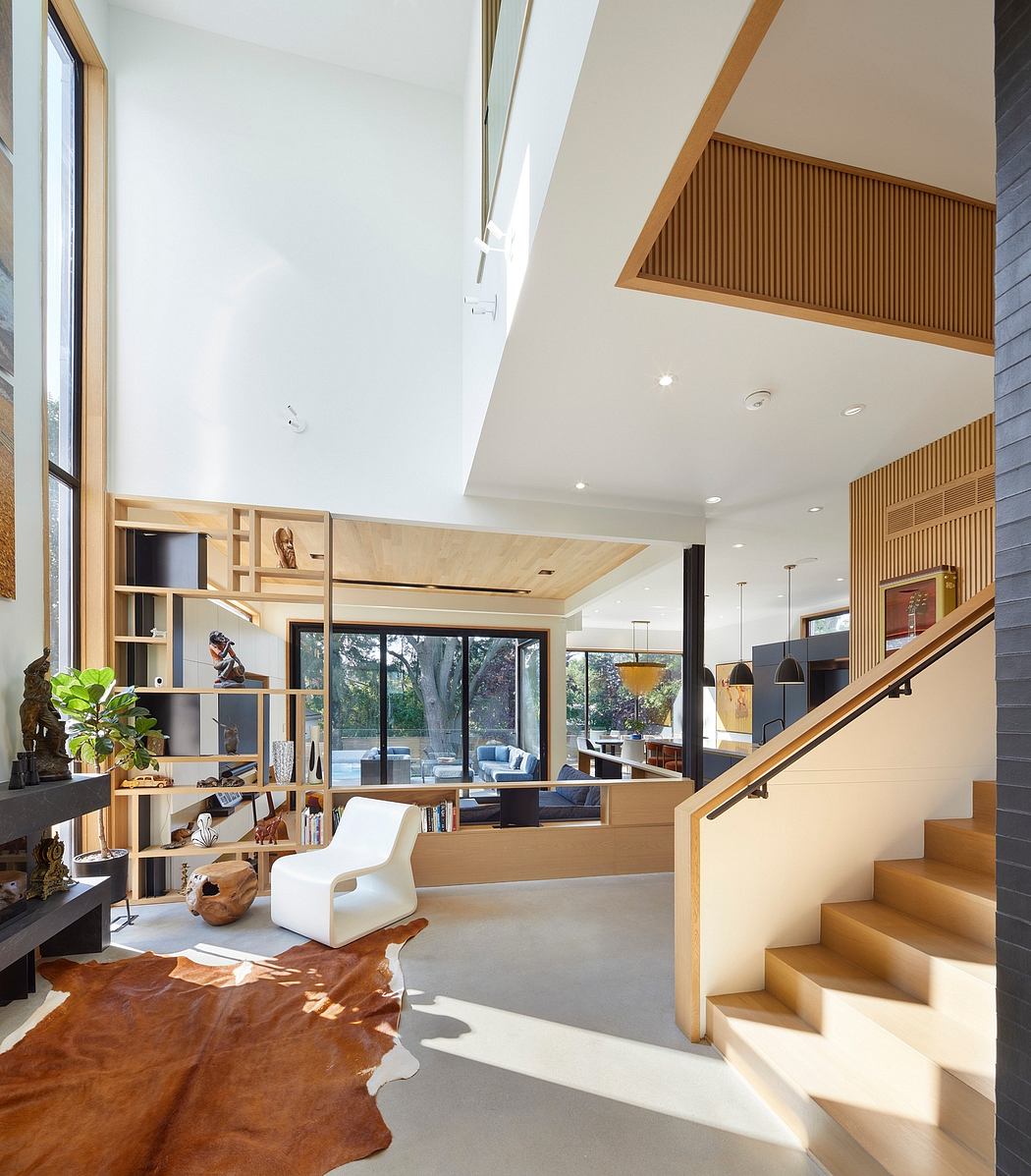 Stunning open-concept living space with wooden accents, shelving, and staircase.