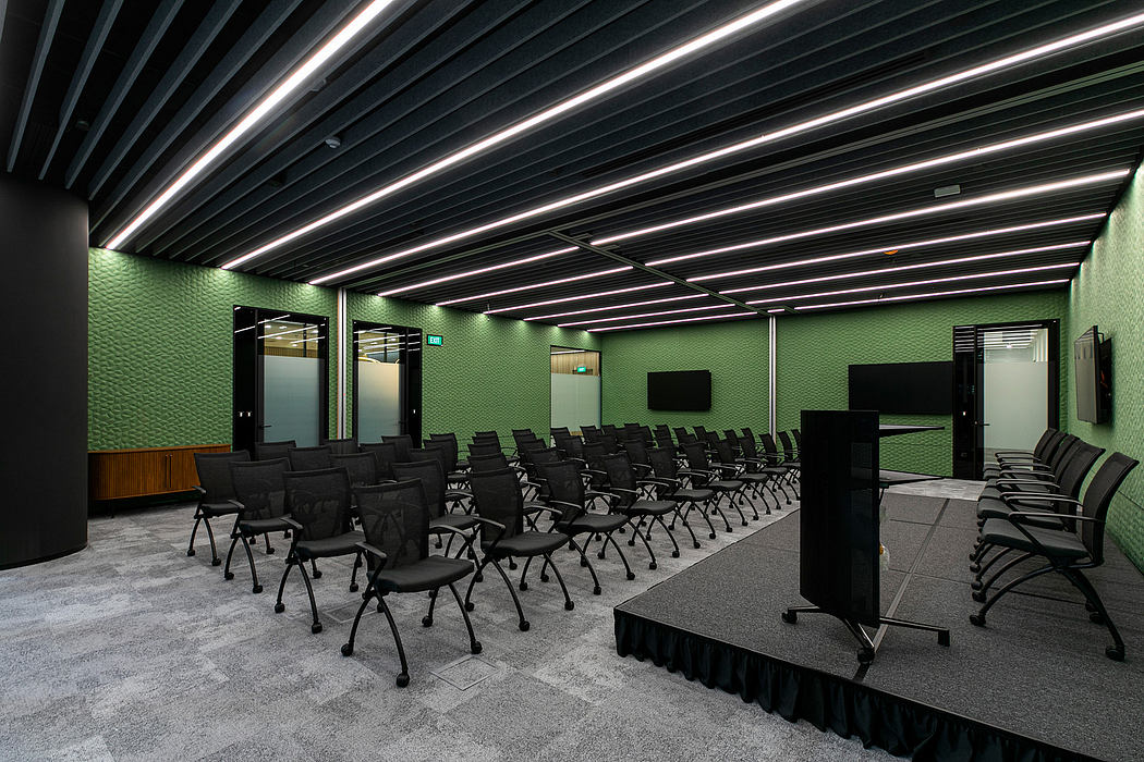 A modern conference room with rows of chairs, black furniture, and a sleek, minimalist design.