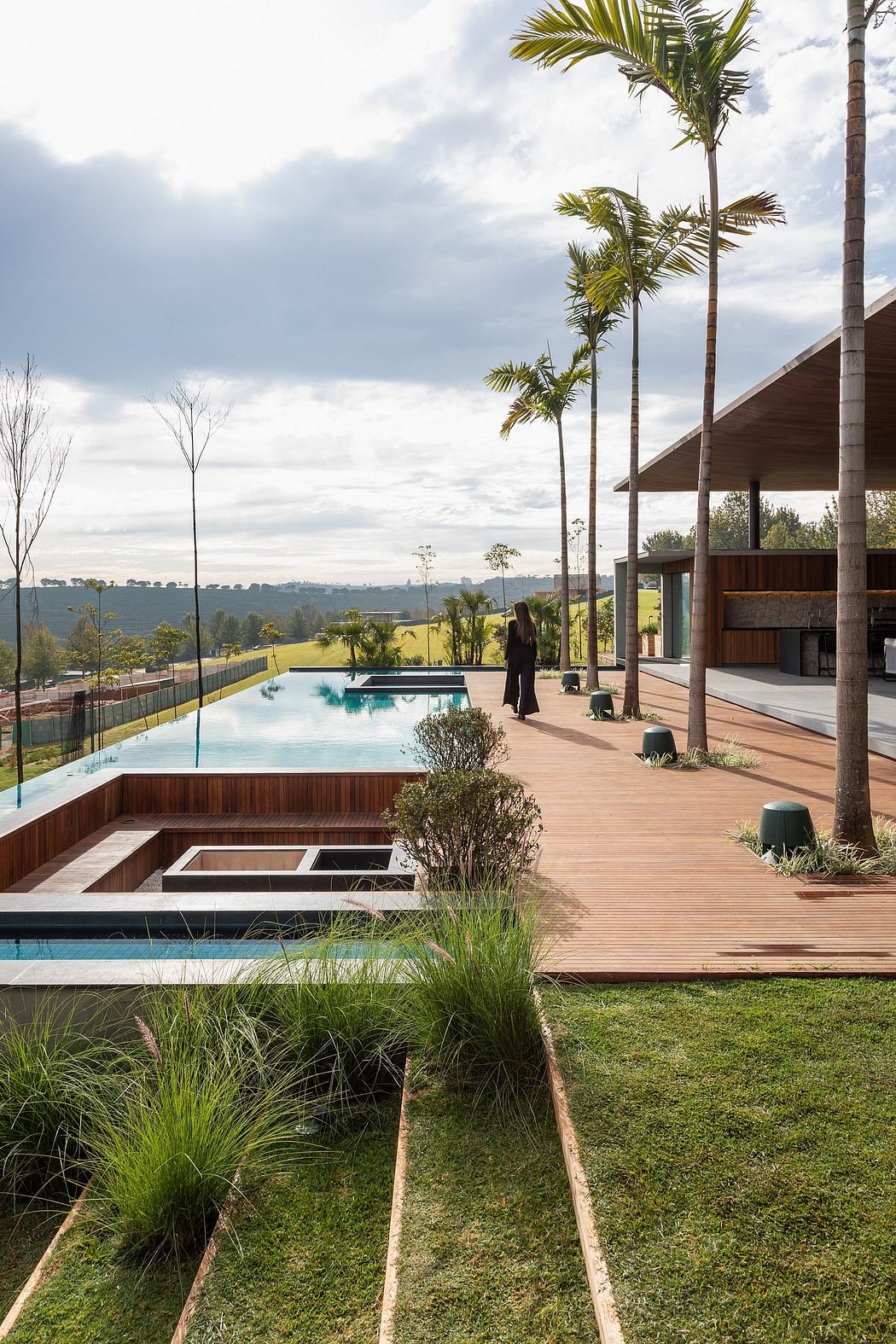 A scenic outdoor pool area surrounded by lush greenery and a modern wooden structure.