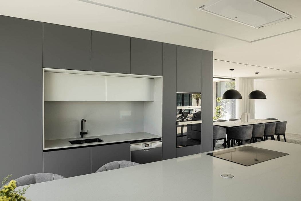 Modern, monochromatic kitchen with sleek cabinets, built-in appliances, and minimalist dining area.