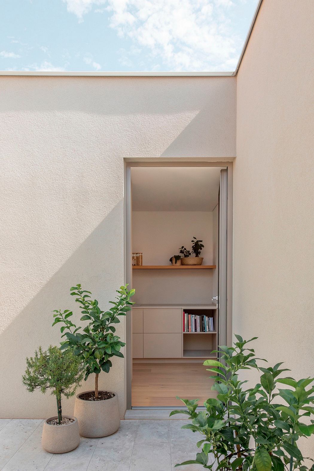 Modern architectural design with a built-in shelf, potted plants, and an inviting entryway.